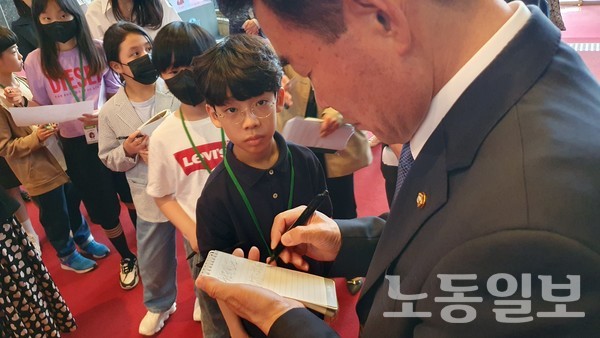김진표 국회의장이 3일 오후 국회에서 '국회견학 프로그램'에 참가한 권유빈 학생에게 사인을 해주고 있다. (사진 = 강봉균 기자)